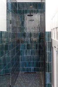 a bathroom with a shower with blue tiles at Boho Chic Studio Stellenbosch in Stellenbosch