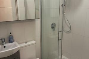 a white bathroom with a shower and a sink at Wimbledon 2 Bed Tennis & Travel in London