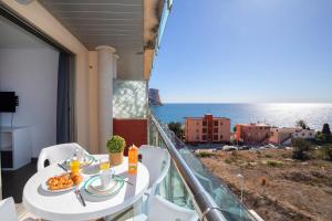 a balcony with a table with food and a view of the ocean at Homeincalpe Borumbot in Calpe