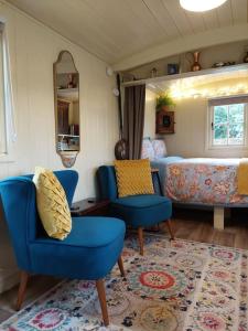 a living room with blue chairs and a couch at The Humble Hut in Wooler