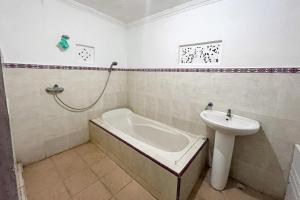 een badkamer met een bad en een wastafel bij Tebluess Guesthouse Gianyar RedPartner in Bedahulu