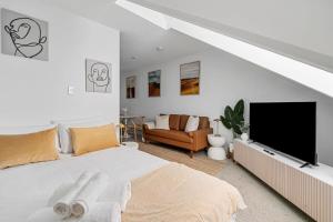 a white bedroom with a bed and a flat screen tv at Modern Studio Retreat in Crown St with AirCon in Sydney