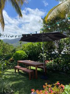 a picnic table with an umbrella and a bench at kaz Lé pa si Ô in La Rivière