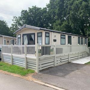 a tiny house with a white fence in front at Poppy 44 in Ferndown