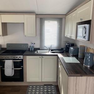 a kitchen with white cabinets and a sink and a stove at Poppy 44 in Ferndown