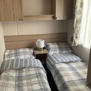 two twin beds in a room with a table at Poppy 44 in Ferndown