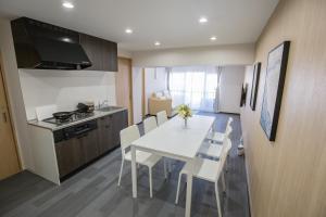 Una cocina y un comedor con una mesa y sillas blancas. en 1min walk to Higashi Shinjuku sta 8PPL Shinjuku Gyoen丶 National Garden丶 Kabukicho丶 Shinjuku Station丶 Golden Gai丶 Tokyo Metropolitan Government Building YYoQA, en Tokio