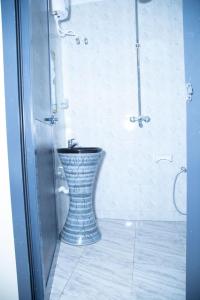 a bathroom with a blue and white vase in a shower at Bwawani Gardens in Songea