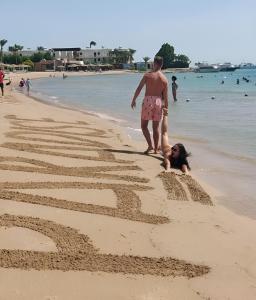 Ein Mann und ein Mädchen spielen im Sand am Strand in der Unterkunft Eagles Paradise Abu Soma Resort in Hurghada