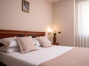 1 dormitorio con 1 cama con sábanas y almohadas blancas en Hotel SAN PIO, en San Giovanni Rotondo