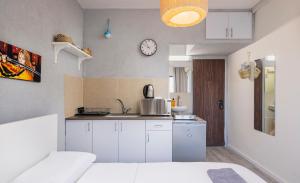 a kitchen with white cabinets and a clock on the wall at Ran's Cozy Hotel Style apt in Tel Aviv