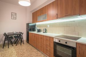 - une cuisine avec des placards en bois, une table et un réfrigérateur dans l'établissement Golden Comfort By Greece Apartments, à Athènes