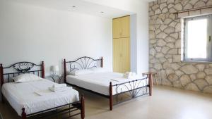 a bedroom with two beds and a stone wall at Guest House Suga 1 in Qeparo