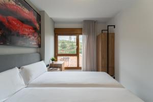 Un dormitorio con una gran cama blanca y una ventana en Bilbao Apartamentos Atxuri en Bilbao