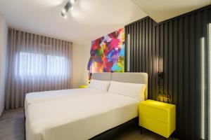 Un dormitorio con una cama blanca y una pintura en la pared en Bilbao Apartamentos Atxuri, en Bilbao