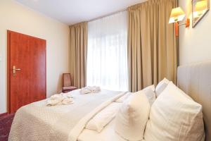 um quarto com uma cama com almofadas brancas e uma janela em Atol Spa em Świnoujście