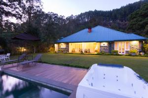 a house with a wooden deck next to a pool at Rockbourne Bungalow in Kandy