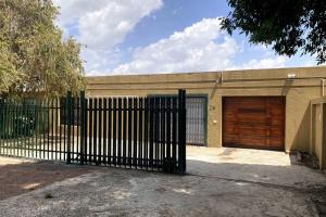 une porte noire en face d'un bâtiment avec garage dans l'établissement Gorgeous 2-Bedroom apartment, à Secunda