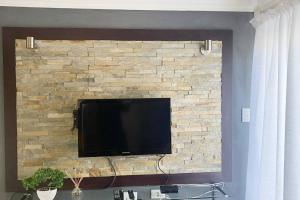a flat screen tv mounted on a brick wall at Gorgeous 2-Bedroom apartment in Secunda