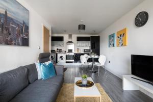 a living room with a gray couch and a kitchen at Modern 2 bed in central MK, Free Parking, Smart TV in Buckinghamshire