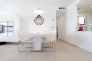 a white dining room with a white table and chairs at Infinity View - Access to hot tubs & pools in Arenales del Sol