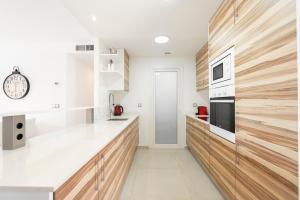 a kitchen with white countertops and wooden cabinets at Infinity View - Access to hot tubs & pools in Arenales del Sol