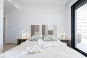 a white bedroom with a large bed with two tables at Infinity View - Access to hot tubs & pools in Arenales del Sol