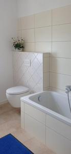 a white bathroom with a toilet and a tub at Jugendstilvilla voll renoviert in Falkenstein