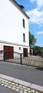 a white building with a fence next to a street at Jugendstilvilla voll renoviert in Falkenstein