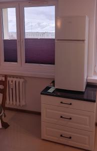 a kitchen with a white refrigerator and two windows at Hostel Reja 54A in Suwałki