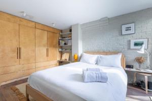 a bedroom with a white bed and a brick wall at Rustic Modern 1BD Flat wGarden Stoke Newington! in London