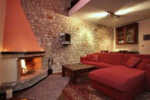 a living room with a red couch and a fireplace at Αέσκω in Vitina