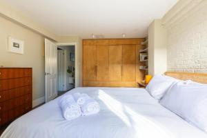 a bedroom with a white bed with towels on it at Rustic Modern 1BD Flat wGarden Stoke Newington! in London