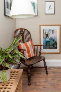 einen Stuhl mit orangefarbenem Kissen im Wohnzimmer in der Unterkunft Rustic Modern 1BD Flat wGarden Stoke Newington! in London