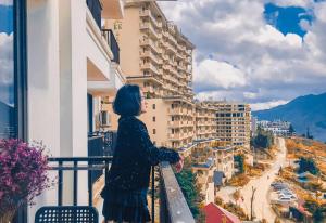 a woman standing on a balcony looking out at a city at Roxana Sapa Hotel - by Bay Luxury in Sapa