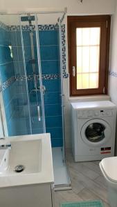 ein Bad mit einer Dusche und einer Waschmaschine in der Unterkunft Villino Mimosa in Costa Rei
