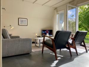 a living room with a couch and a table and chairs at Heide 6pers Waterfront house at a typical dutch canal, by the Lauwersmeer in Anjum