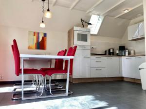 a kitchen with red chairs and a white table at Heide 6pers Waterfront house at a typical dutch canal, by the Lauwersmeer in Anjum