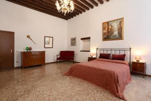 a bedroom with a bed and a chair and a chandelier at Flat with canal view near San Marco in Venice