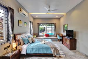 a bedroom with a blue bed and a television at ELIVAAS Radhyam Luxe 2BHK Villa with Pvt Pool in Udaipur