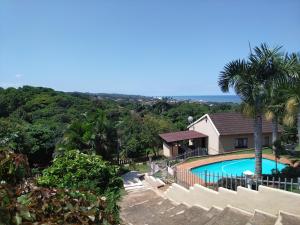 una casa con piscina y una palmera en Klein Paradys, en Port Shepstone