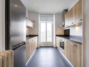 a kitchen with wooden cabinets and a large window at Residence Louis Quartier Centre Ville in Vittel
