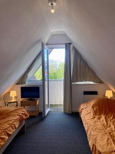 a attic bedroom with two beds and a window at am Deich 6 pers House with a private terrace behind a dike by the Lauwersmeer in Anjum