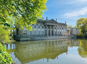 a large building with a reflection in the water at Spacious Apartment with 3 meter ceilings, Powiśle, The Old Town in Warsaw