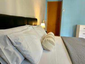 Cama blanca con cabecero negro y almohadas blancas en Sperlonga Paradise Central Apartment en Sperlonga