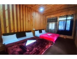 a bedroom with two beds in a wooden cabin at Hotel Auli Inn, Joshimath in Joshīmath