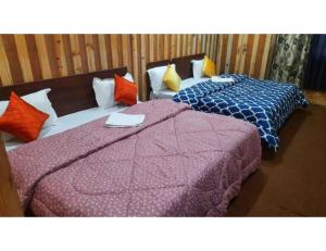 two beds sitting in a room with at Hotel Auli Inn, Joshimath in Joshīmath