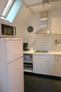 AnjumにあるNatascha 6pers House Near Lauwersmeer National Parkのキッチン(白いキャビネット、白い冷蔵庫付)
