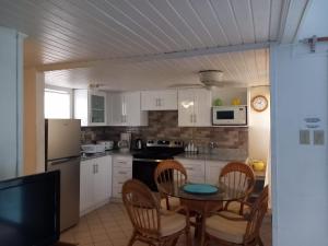 una cocina con mesa y sillas y una cocina con armarios blancos. en Sealofts On The Beach en Frigate Bay