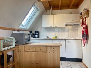 una pequeña cocina con armarios blancos y una ventana en De Druif 6 pers holiday home close to the National Park Lauwersmeer, en Anjum